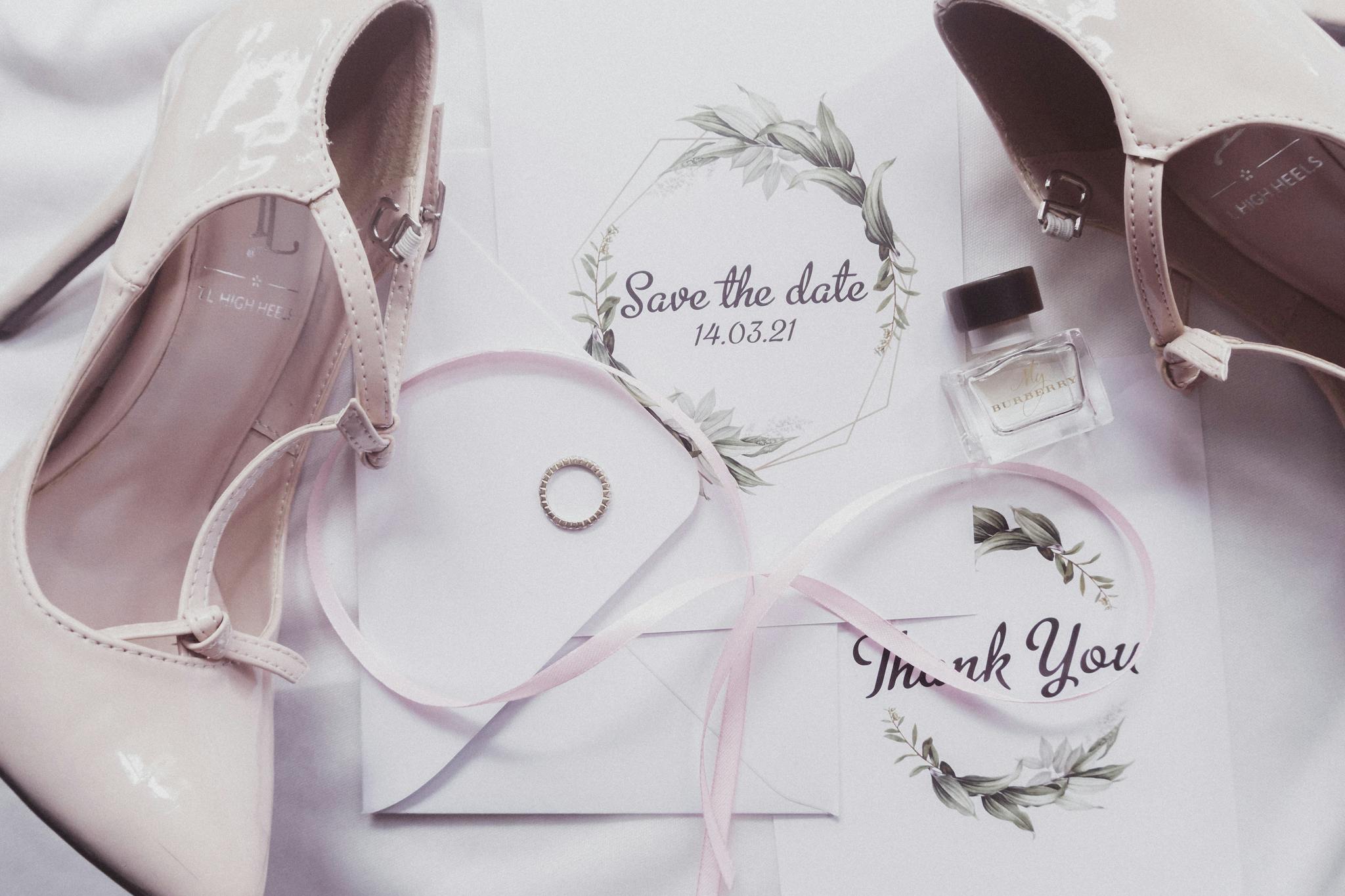A chic flat lay of wedding essentials including heels, perfume, and invitations.