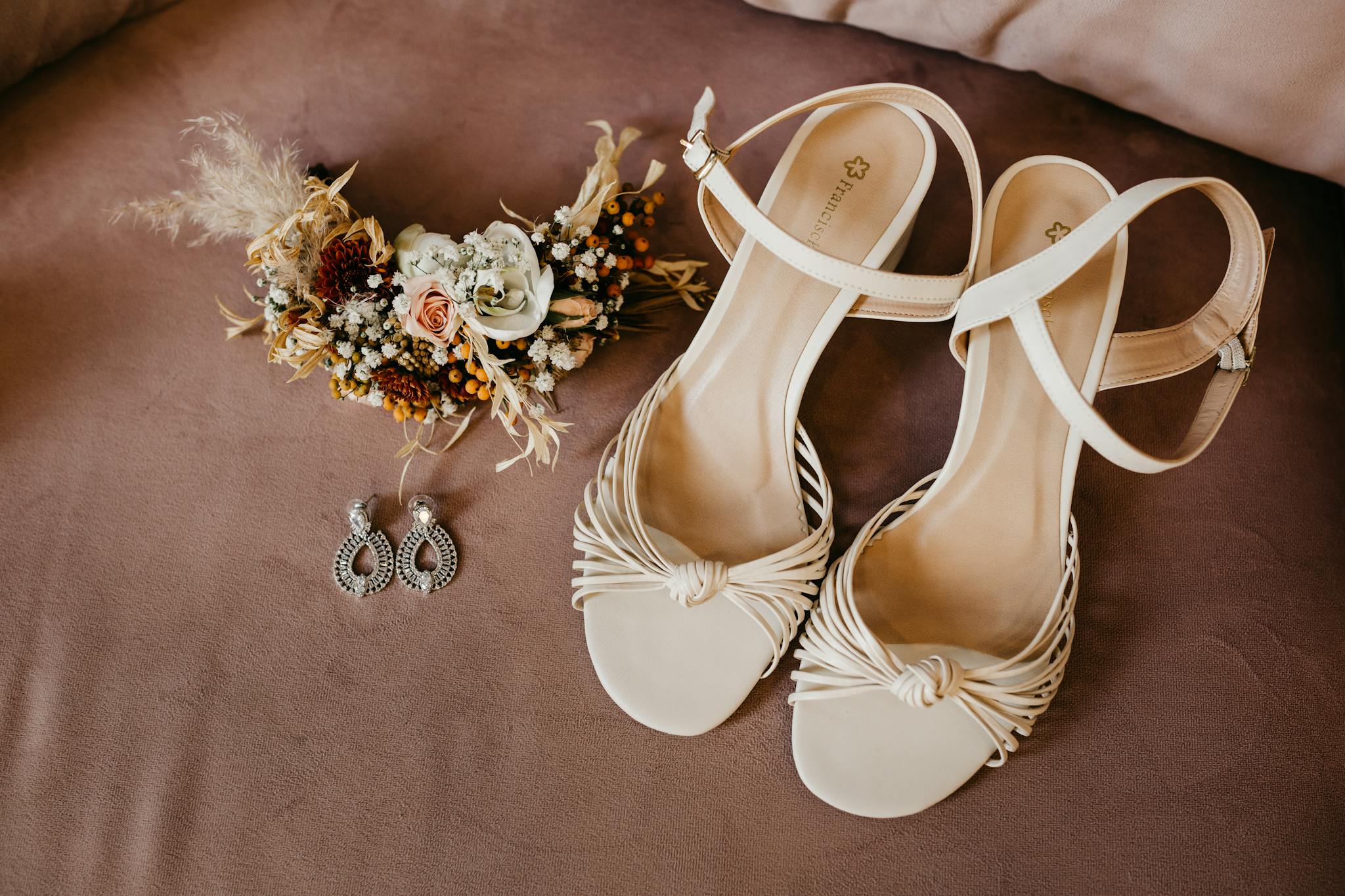 Beautiful flat lay of bridal accessories with shoes, earrings, and floral arrangement, perfect for weddings.