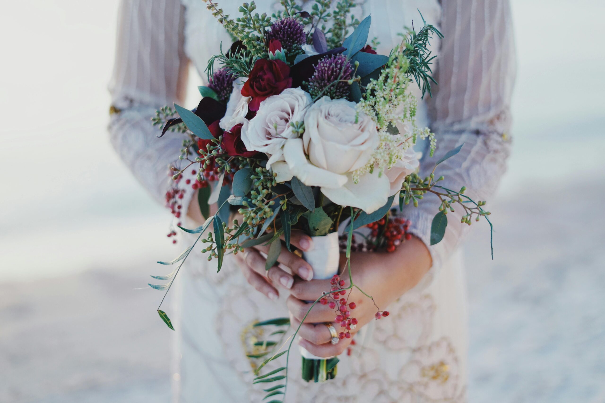 Close-up of a bride holding a beautiful bouquet at an outdoor wedding ceremony.