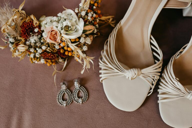Wedding accessories including sandals, earrings, and a floral bouquet in a stylish flat lay.